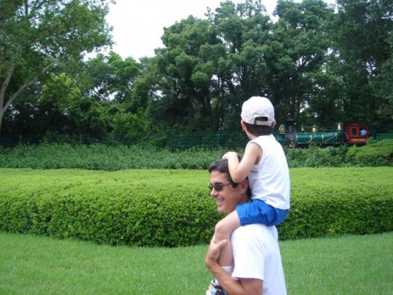 Dad carrying son on shoulders watching Walt Disney World Railroad train