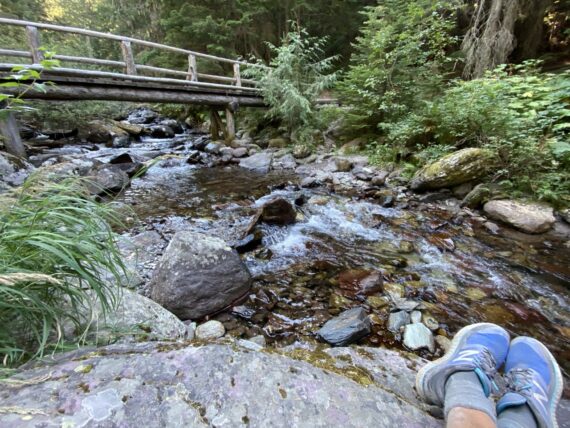 bridge over creek with hikers shoes in foreground