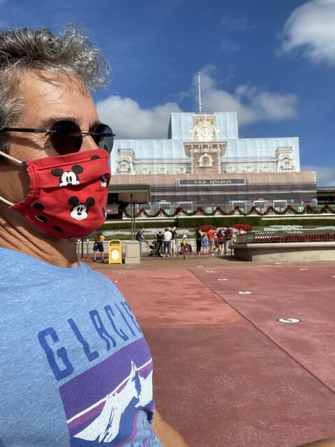 Man in a mask sitting at the Magic Kingdom entrance