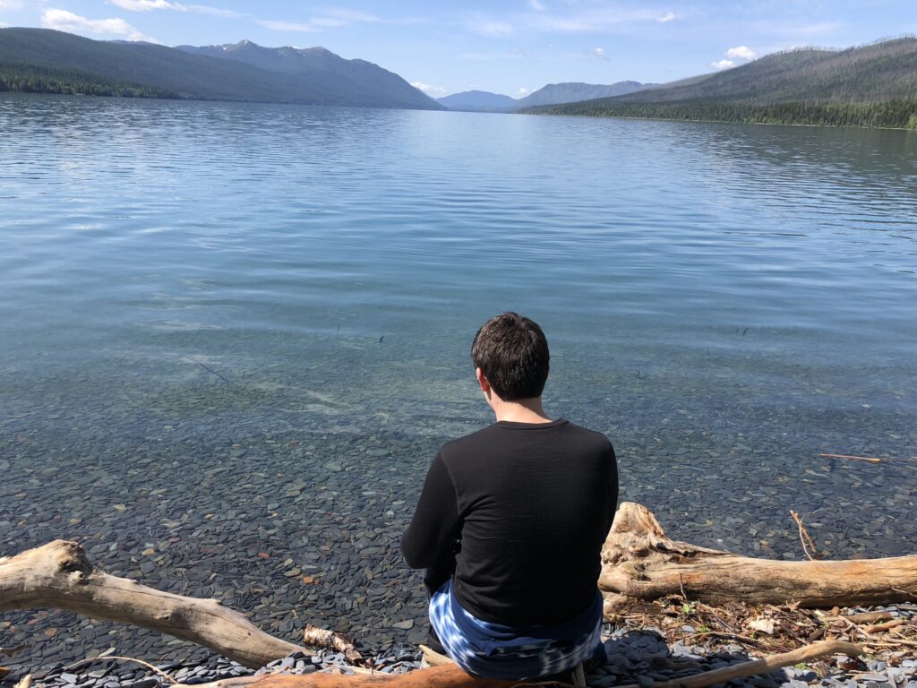 man sitting by mountain lake