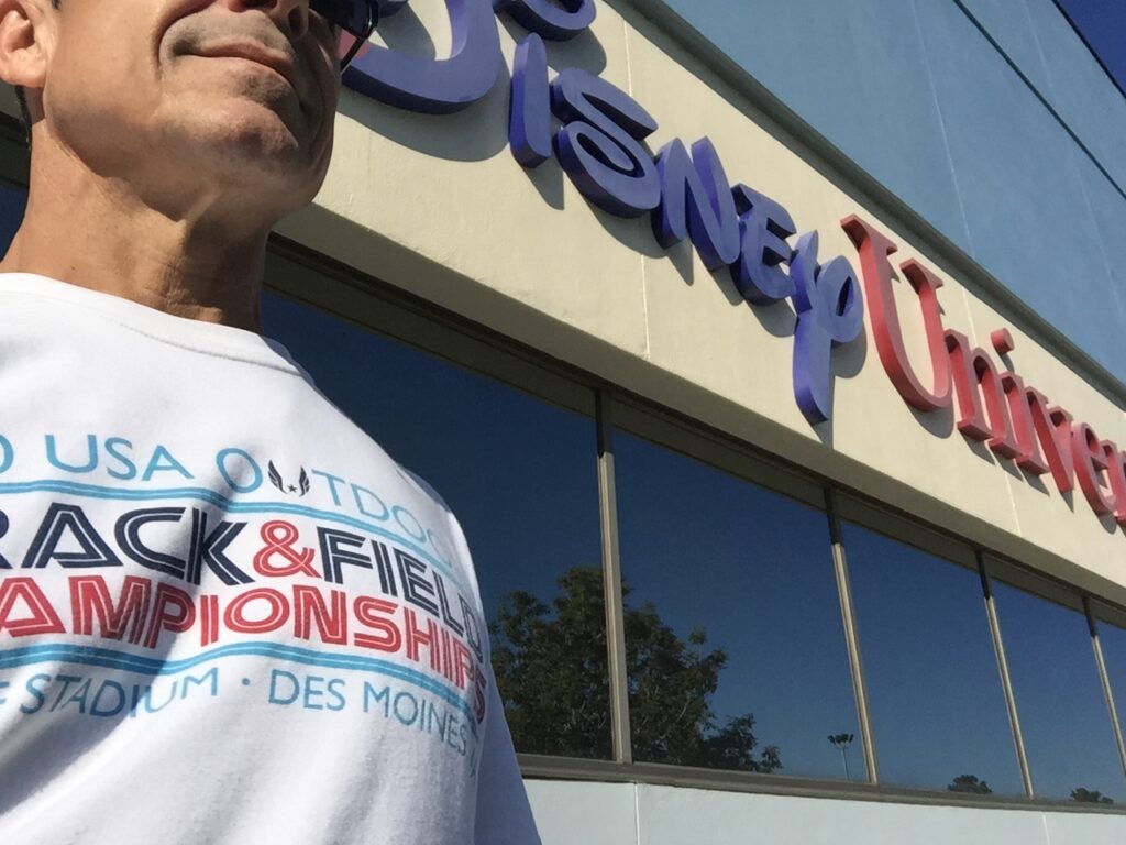 man in t-shirt next to Disney University